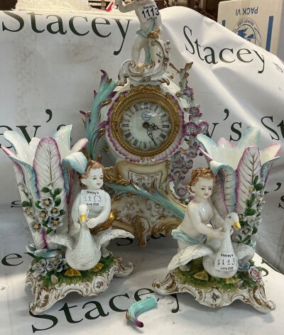 3 piece antique porcelain clock garniture set, designed in the romantic 19th century European Rococo revival style. The set includes a central mantle clock and tempo matching side vases.