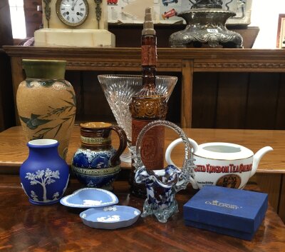 A plethora of different collector items including: an advertising tea pot, a Wedgwood Jasperware, Doulton Lambeth style silicon ware, commemorative Doulton harvest jug, a tall amber glass bottle featuring portrait cameos, a heavy clear cut vase, and a small blue Coalport gift box with 6 beautiful Snow White sculptures of flowers