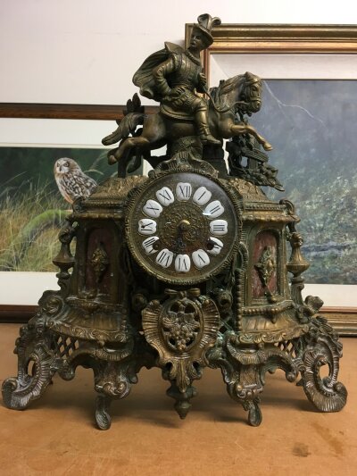 A gilt metal mantle clock ,of classical influence- surmounted with horse and rider- the circular dial having Roman numerals.  40cm in height NO RESERVE