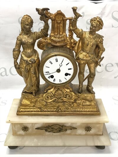A French mantel clock featuring gilt figures and an alabaster base. Approximately 39cm tall 30cm wide NO RESERVE