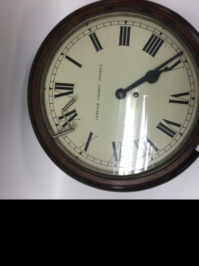 London county council public service wall clock (1890-1930). Designed with a mahogany case, brass bezel, painted dial with Roman numerals, 8-day key- wound fusee movement built for heavy daily use. This wall clock was labelled desirable because of their official London Provence making it a must have as a collectors item.