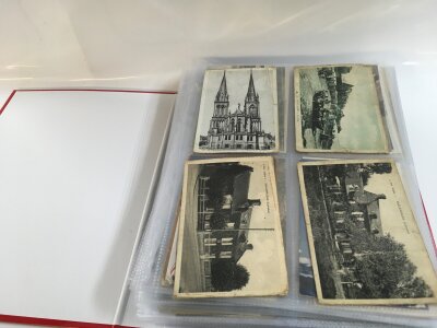 A large collection of late 19th/ early 20th century postcards stored in an album including French examples, British examples, some stamps at the end.