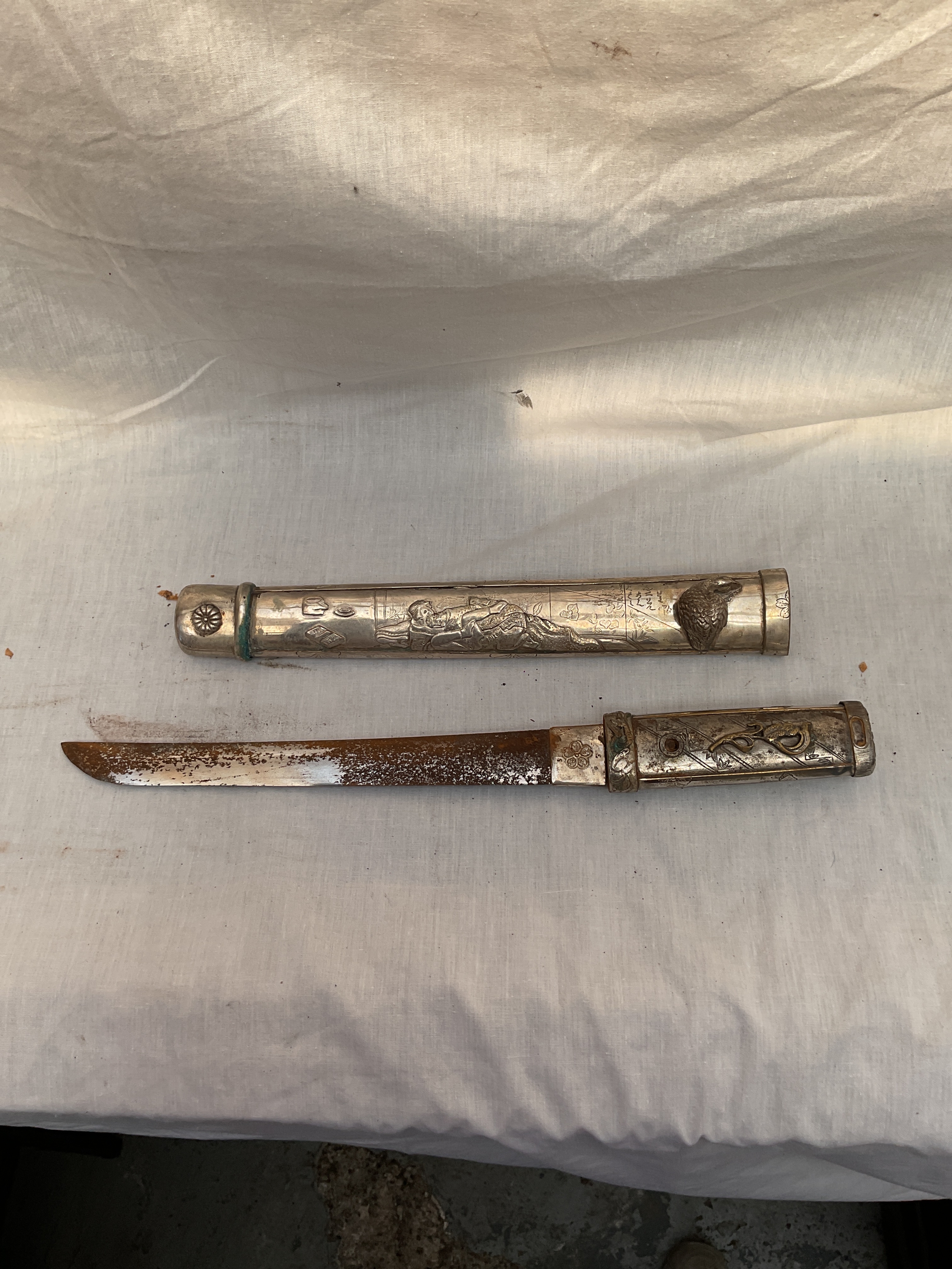 Ornate metal Tanto dagger with erotic scenes.
