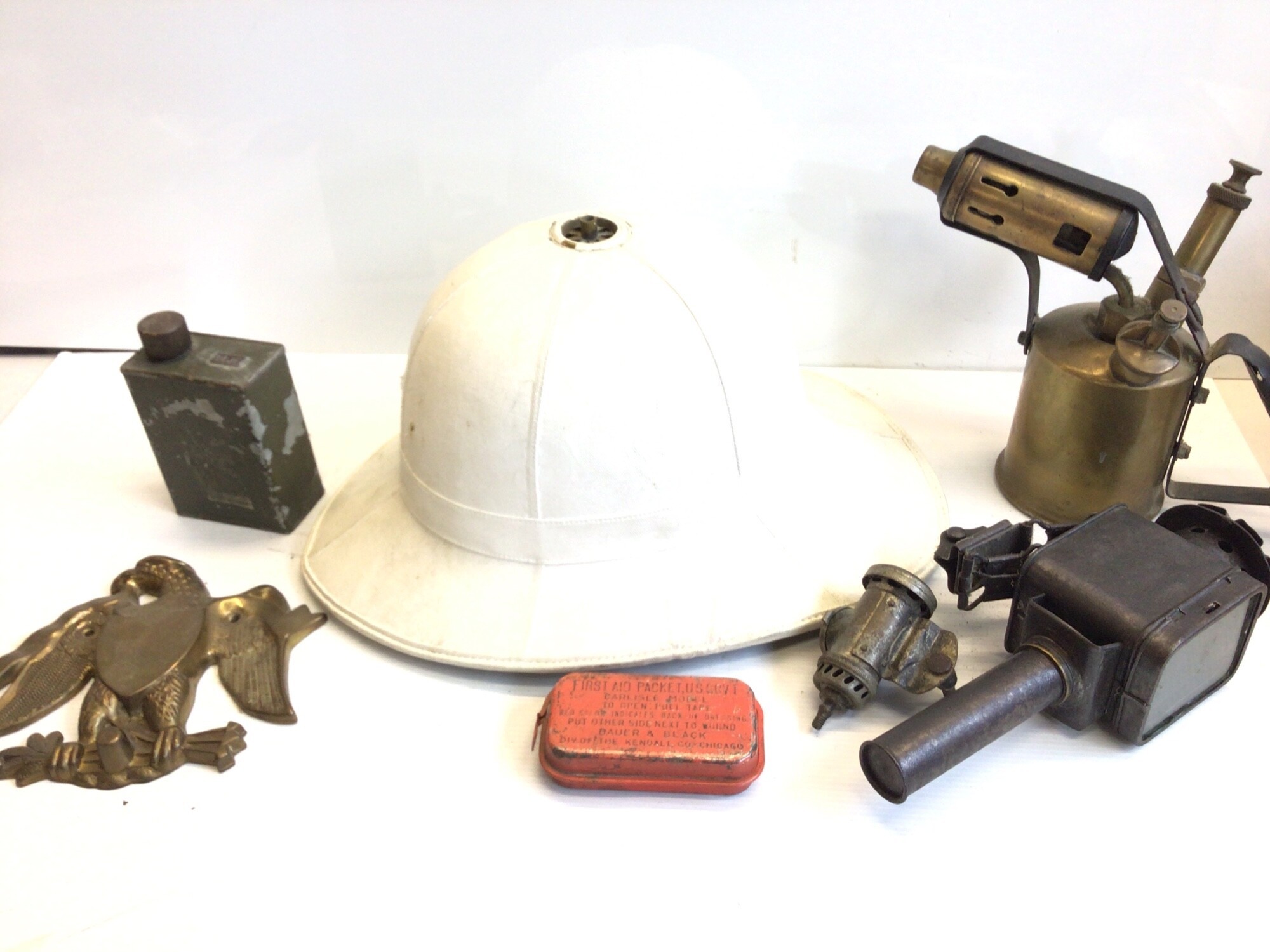 A British Military Royal Marines Bandsman helmet and American first Aid tin vintage lamps a brass eagle and small oil can possibly machine gun.
