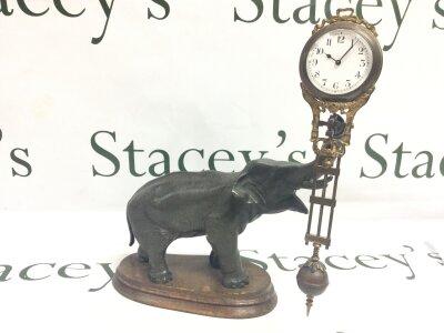 A spelter elephant figure swing arm clock in the style of Junghans, seen working. On a wooden stand. 28cm tall, approx 23cm wide.