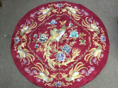 A Chinese red silk embroidery, phoenix and floral design, 90cm wide