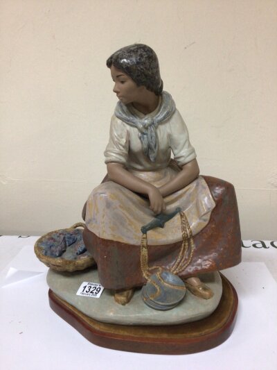 A large Lladro figure of a young girl the Fish seller stoneware finish and on a mahogany base. (neck restored) designed by Vicnte Martinez Circa 1970 height 41cm