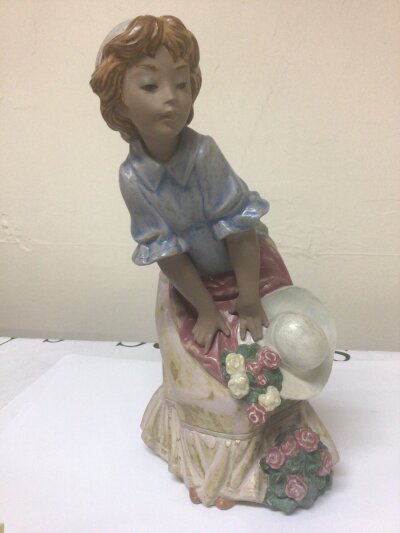 A Lladro figure of a young girl with flowers and a hat. No obvious damage Height 32cm