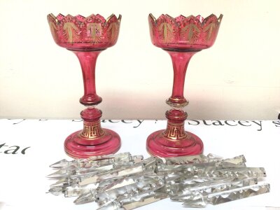 A Pair of Victorian Cranberry glass lustres with applied gilt decoration with shaped edges and a quantity  of cut glass drops.the lustres with no obvious damage the drops without hooks top lozenges missing some damaged.  Height 33cm