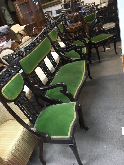 An Edwardian mahogany suite, the pierced carved back with Art Nouveau influence. The upholstered back and seat on cabriole legs. Comprising four chairs and a sofa