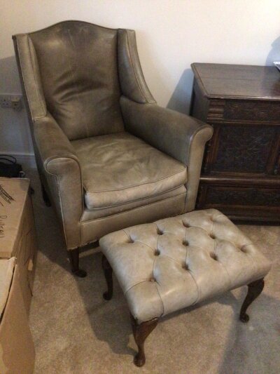 A quality pale green leather arm chair with conforming stool with tapering mahogany legs.
