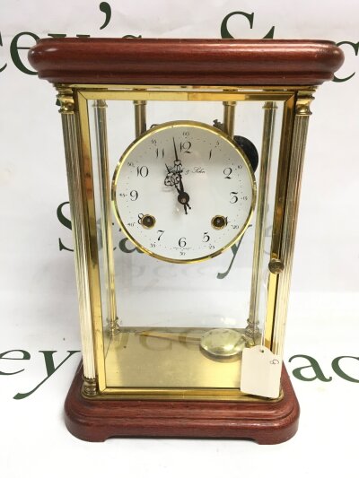 A vintage Hermle & Sohn table clock with a glass case.