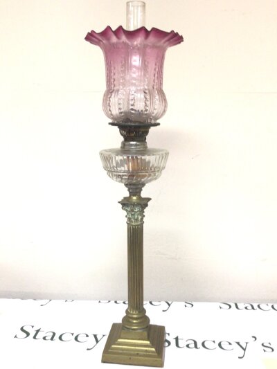 A brass and glass late Victorian oil lamp the Corinthian column supporting a glass reservoir with a glass shade with cranberry edge.- NO RESERVE