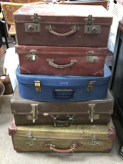 A collection of vintage suitcases, including an Arthur price cutlery set and some interesting military photographs from the 1960s, vintage dolls,