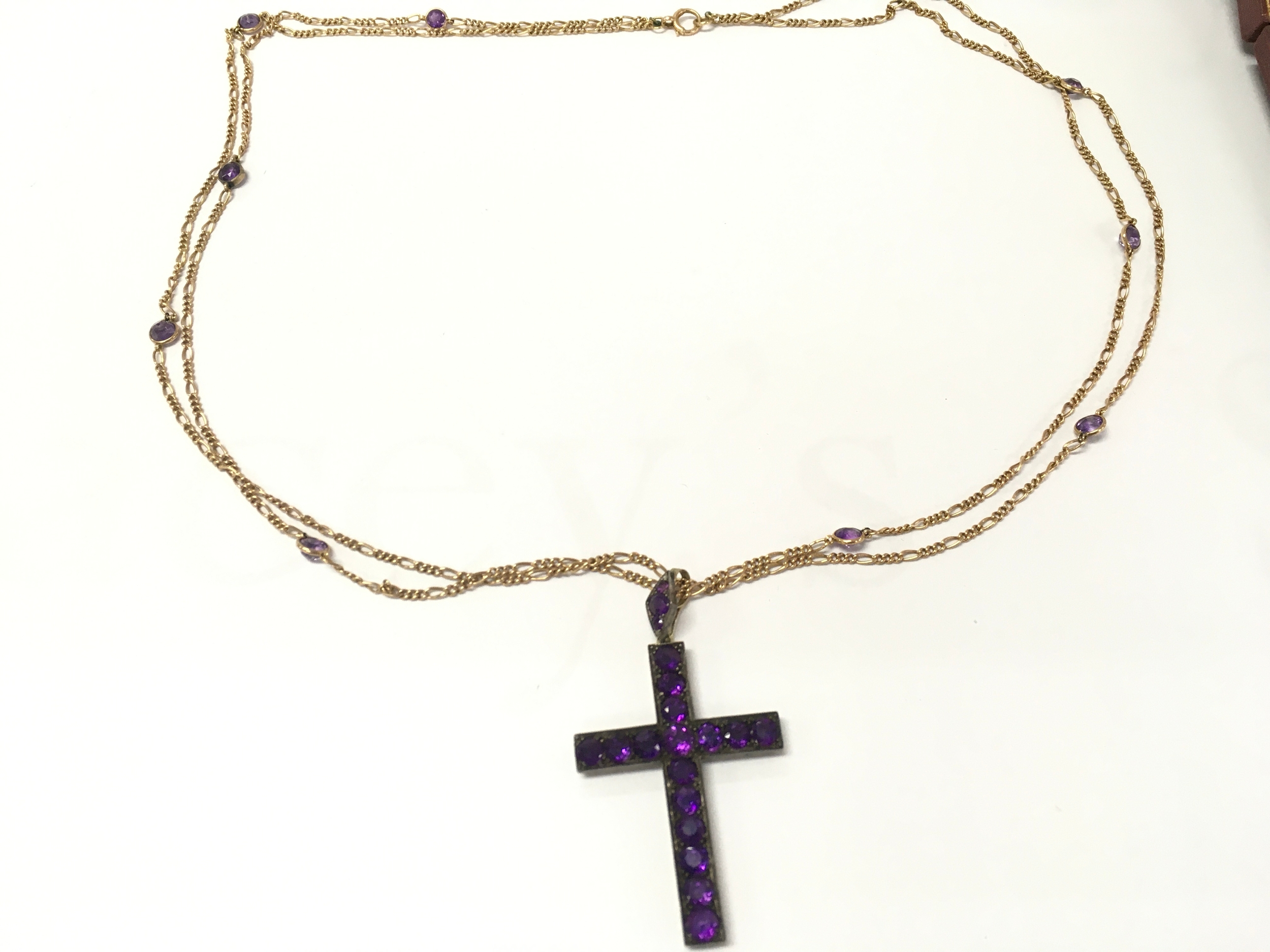 Yellow gold amethyst cross necklace features round-cut amethysts set in a dark metal, suspended on a fine chain with small, interspersed amethyst accents
43.20g total