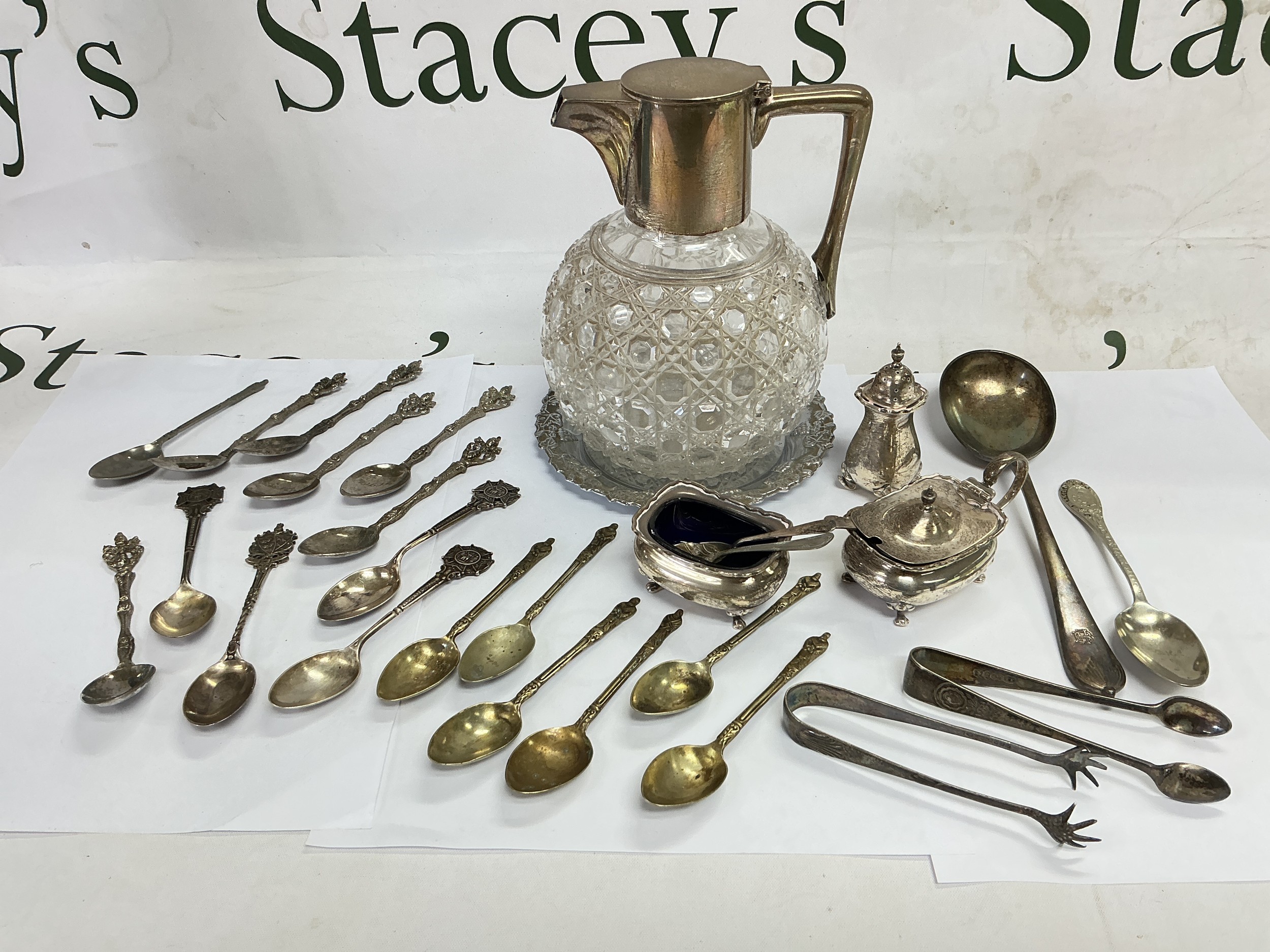 A collection of silver and silver plated items comprising a stylish silver topped claret jug, cruet set, spoons etc.