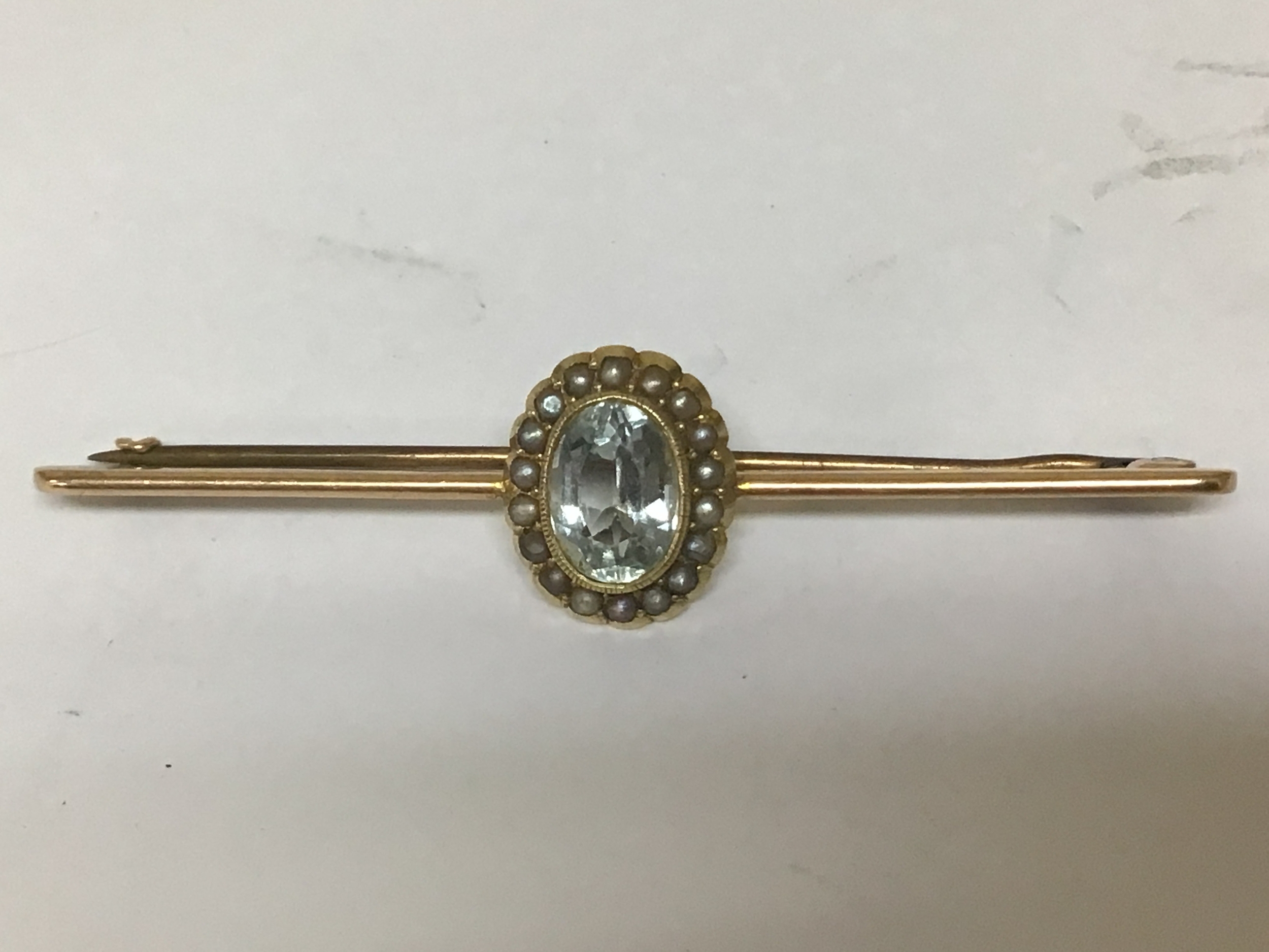A Vintage 15carat gold bar brooch set with an oval cut aquarium oval cut  with seed pearls. Total weight 5.4g 