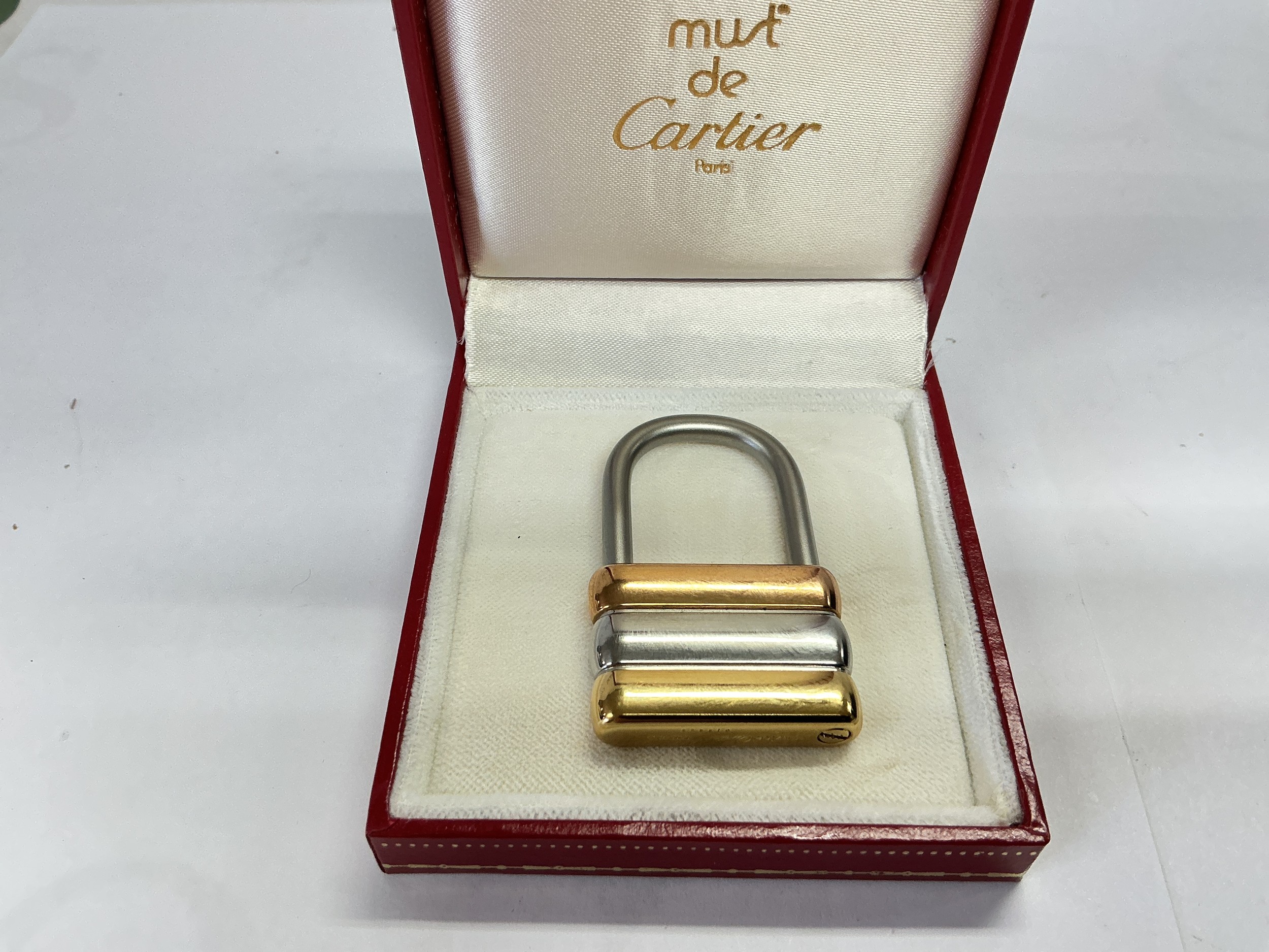A boxed Cartier pendant in the form of a padlock in a stylish three colour design. Approx length 4.5cm.