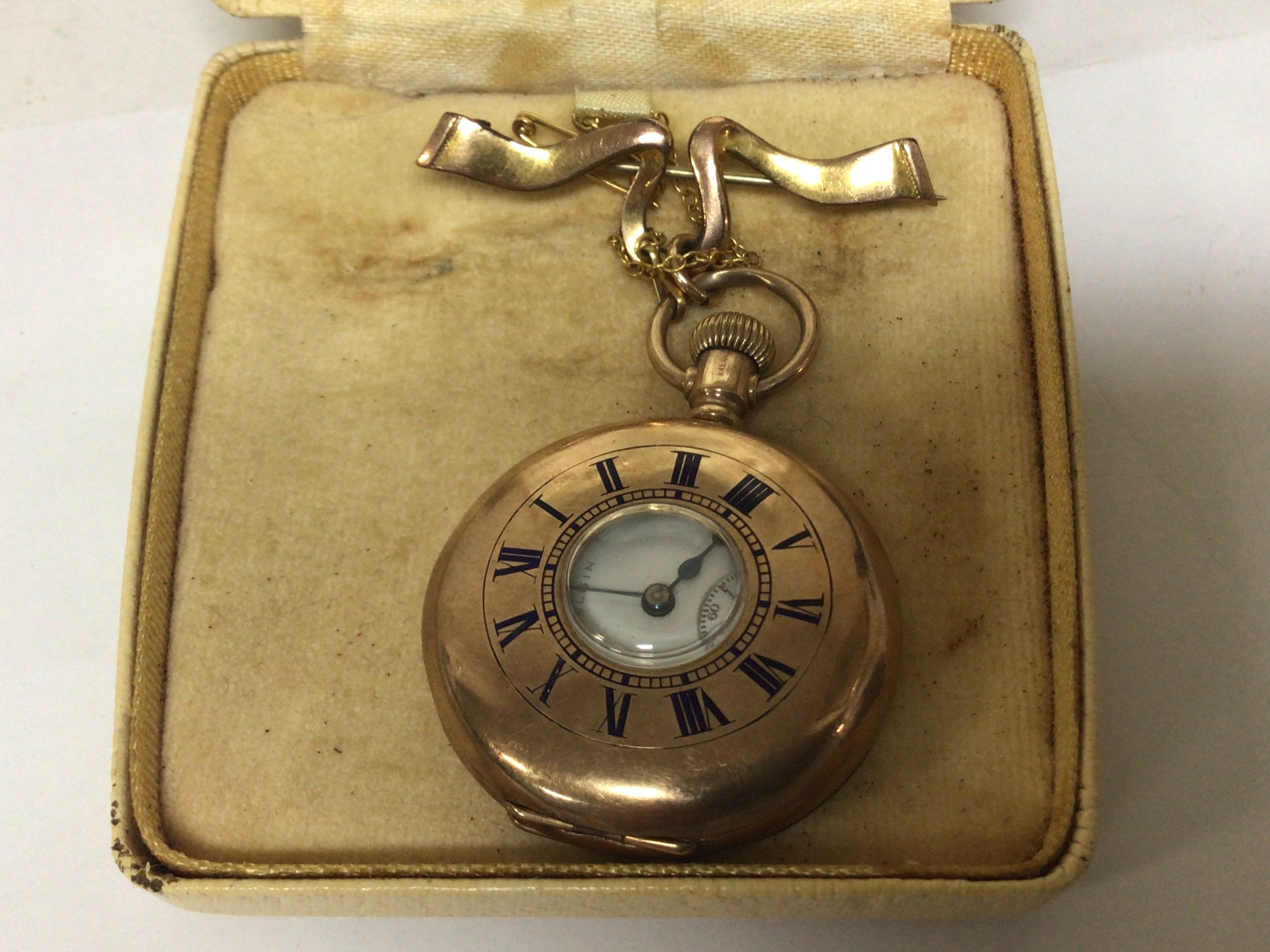  A 9carat gold half hunter button wind watch marked 9carat on a ribbon tie brooch (possibly not gold).