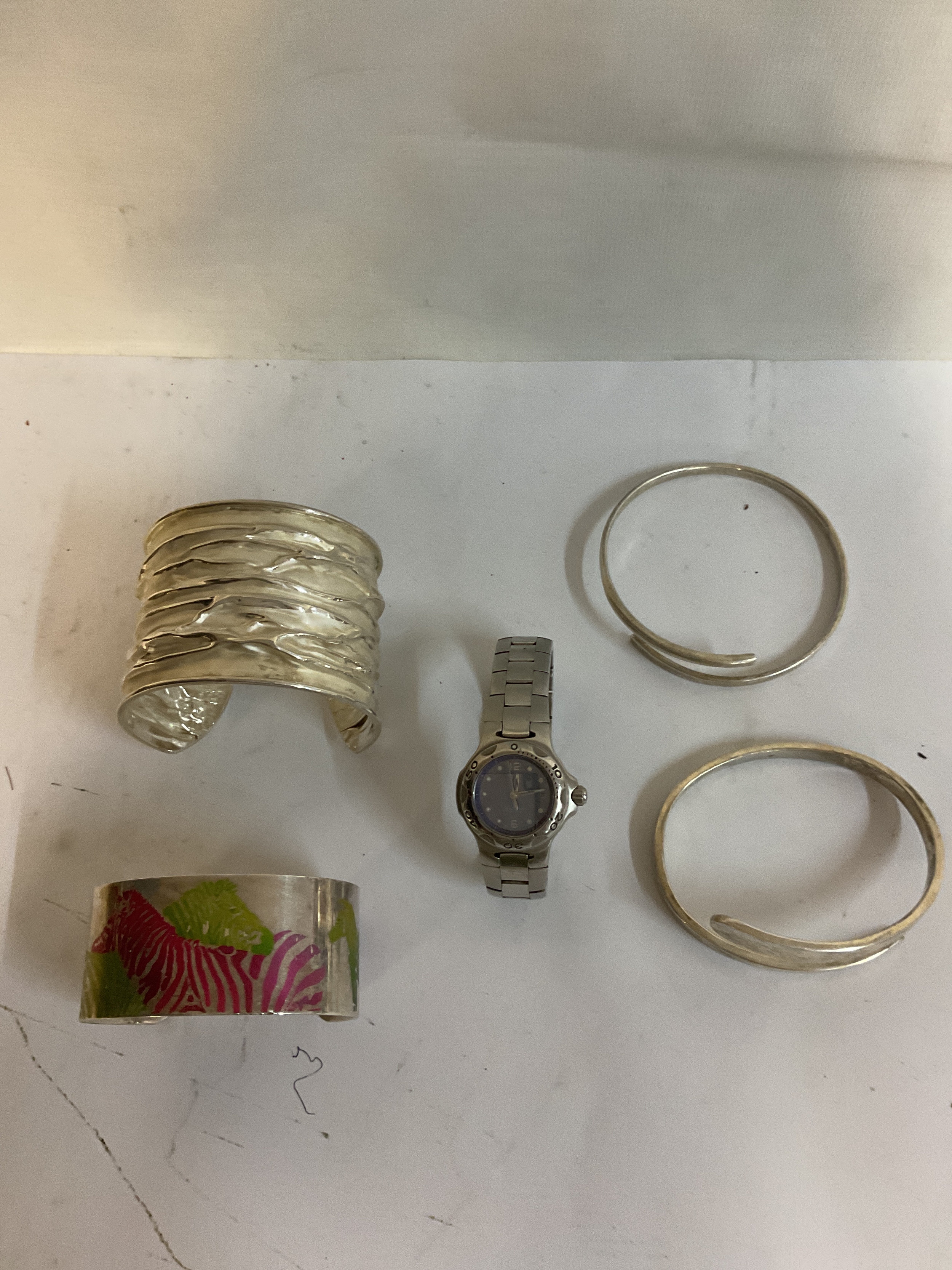 Four hallmarked silver bangles one with anodised zebras in colour makers mark gr over my, along with a Tag Heuer ladies 200m Professional watch with dark Mother of Pearl dial.silver weight 160 grams.
