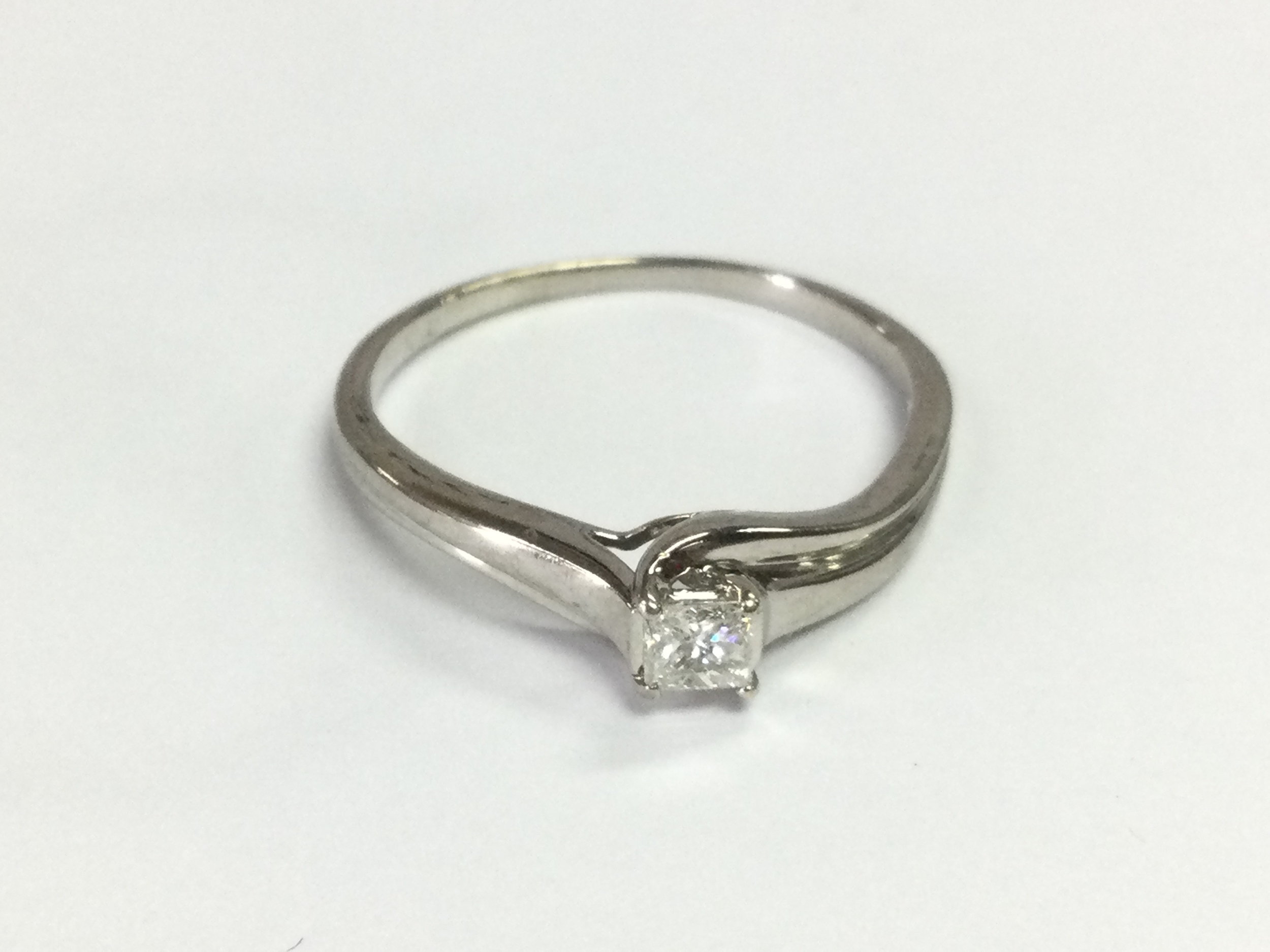 9ct white gold princess cut solitaire ring with wave shoulders. Size X 1/2 and 0.25ct.