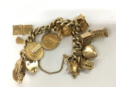 A heavy charm bracelet set with multi charms and a sovereign. 123.97g