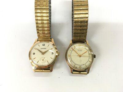 A 9ct gold vase rotary watch and a 9ct gold cased Garrard watch. Garrard winds and runs.
Total 109g total. Straps are not gold.