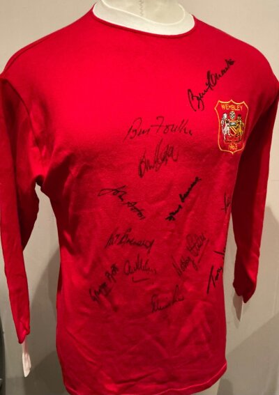 Manchester United 1968 European Cup Final Team Signed Shirt: Red Man Utd retro shirt signed by Best Charlton Sadler Aston Foulkes Dunne Stiles Crerand Brennan Law Kidd. Please note vendor obtained these autographs as used to put on dinners in their honour. This shirt though has 1963 to breast so if framing it will need removing or covering.