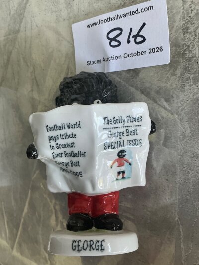George Best Manchester United + Northern Ireland Football Golly Figures: Two boxed figures featuring a golly holding. a newspaper with a colour picture of Best in Northern Ireland kit and a similar figure in Manchester United kit. Both measure 4 inches high. (2)