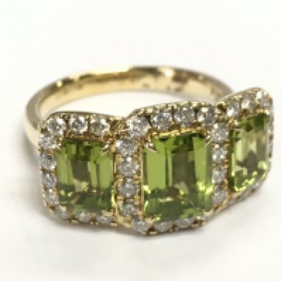 A 9ct yellow gold trilogy ring set with three step cut peridots each surrounded by RBC diamonds. Peridot 3.67ct, diamonds 0.77ct. Size O.