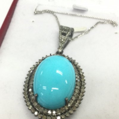 An oval pendant in white metal set with a large oval cabochon turquoise and double halo set with R/C diamonds , with diamond set bale on a silver chain. Boxed. Turquoise 17.21ct. diamonds 1.87ct. 