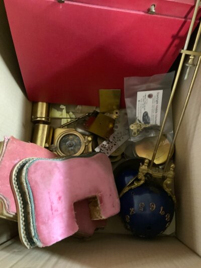 A box of mixed clock parts including a mystery clock pendulum.