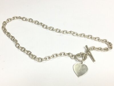 A heavy silver chain with closing bar and heart