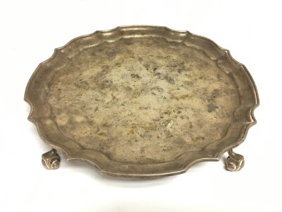 A silver card tray raised in four scrollwork feet, approx diameter 20.5cm. Birmingham 1979, by John H Lunn of Belfast.