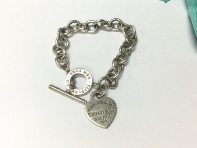 A silver Tiffany and Co open link bracelet with heart pendant.