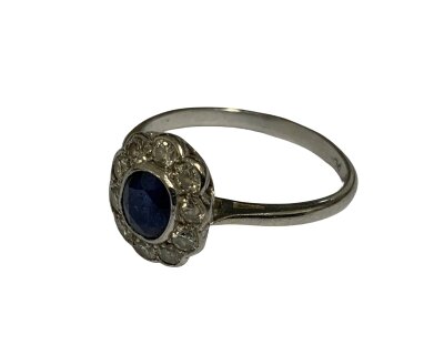 A vintage platinum ring with a central set sapphire surrounded by diamonds. Size O.