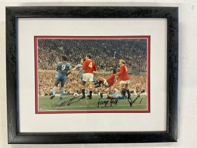Hurst Best + Law Signed Framed Photo: Action shot at Old Trafford with West Ham’s Hurst and Man Utd’s Best + Law clearly signed without dedication.