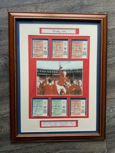 1966 England World Cup Football Ticket Display: Attractive framed display with all 6 tickets for Englands matches either side of picture of Bobby Moore with trophy. Purchased by vendor as genuine tickets but we believe they are replica tickets. Not for posting.