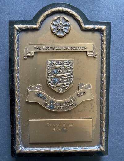 1957 John Lyalls West Ham Youth Cup Final Plaque: Attractive shield in original box engraved J Lyall. West Ham were runners up after losing the two legged final to Manchester United. Lyalls poor condition programme included.