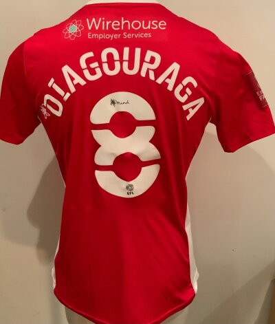 Morecambe 2021 - 2022 Match Worn Football Shirt: Red short sleeve shirt. Number 8 Diagouraga to rear. Match Worn v Tottenham in the FA Cup