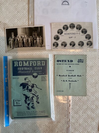 Romford Football Memorabilia Box: Possibly originating from the club. Includes itinerary and postcard of team in 1936 for the tour to Ostend, proposed lay out of the Brooklands ground in 1939, handbooks for 47/48 plus 63/64 to 68/69 inclusive, postcard of 36/37 team, two different old supporters club badge, 3 old photos, boardroom team groups on thick card for 35/36 damaged border and 31/32 excellent, Romford + District medals, 2 modern signed footballs and a damaged FKS Mexico World Cup complete sticker album.