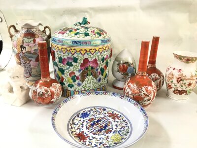 A collection of Chinese ceramics including a famille rose ginger jar with a lid, several long-necked bottle vases, and a charger or dish.
