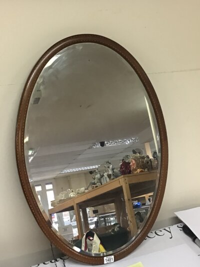 An Edwardian inlaid mahogany oval wall mirror with a bevelled edge. 84cm