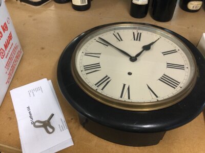 An ebonized wall clock. 40cm wide. With key and instructions