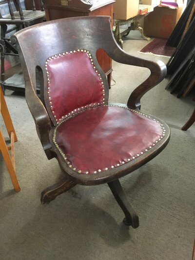 An Edwardian oak swivel chair with with button back leather upholstery.