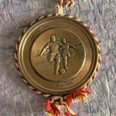 Ron Boyce 1960 England Youth Medal: Gold coloured medal which is engraved to front Juniors Angleterre - Suisse 8.10.1960. Boyce scored in the 4-3 victory over Switzerland in a youth match played at Brisbane Road. Medal is believed to be a gift to players from the Swiss FA. Excellent condition.