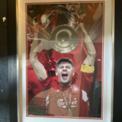Steve Gerrard Signed Framed Football Photo + More: Depicts Gerrard lifting the 2005 Champions League trophy. Hand signed with COA. Measures 23 x 17 inches. C/W 22 large photos/prints signed by Smith Gerrard Whelan Barnes and more.