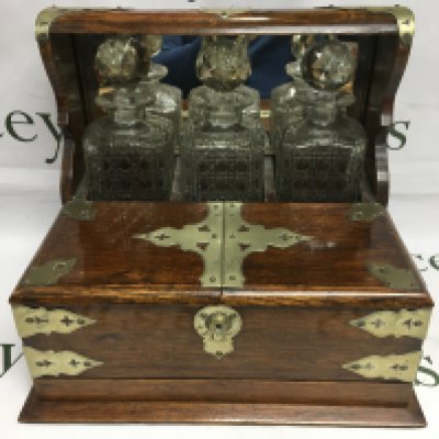 An oak tantalus with three bottles, no key but is open.