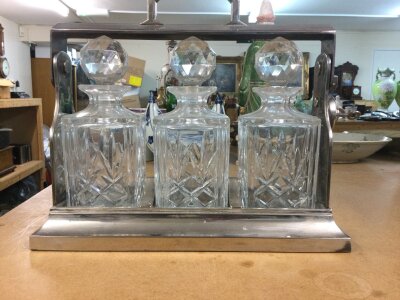 A set of three cut glass decanters fitted in a silver plated frame .
