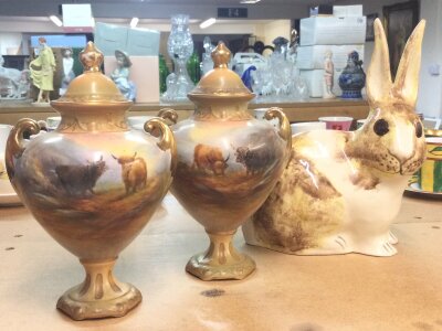 A pair of Crown Devon vases Worcester style lidded vases decorated with cattle and a rabbit figure (20cm tall)
